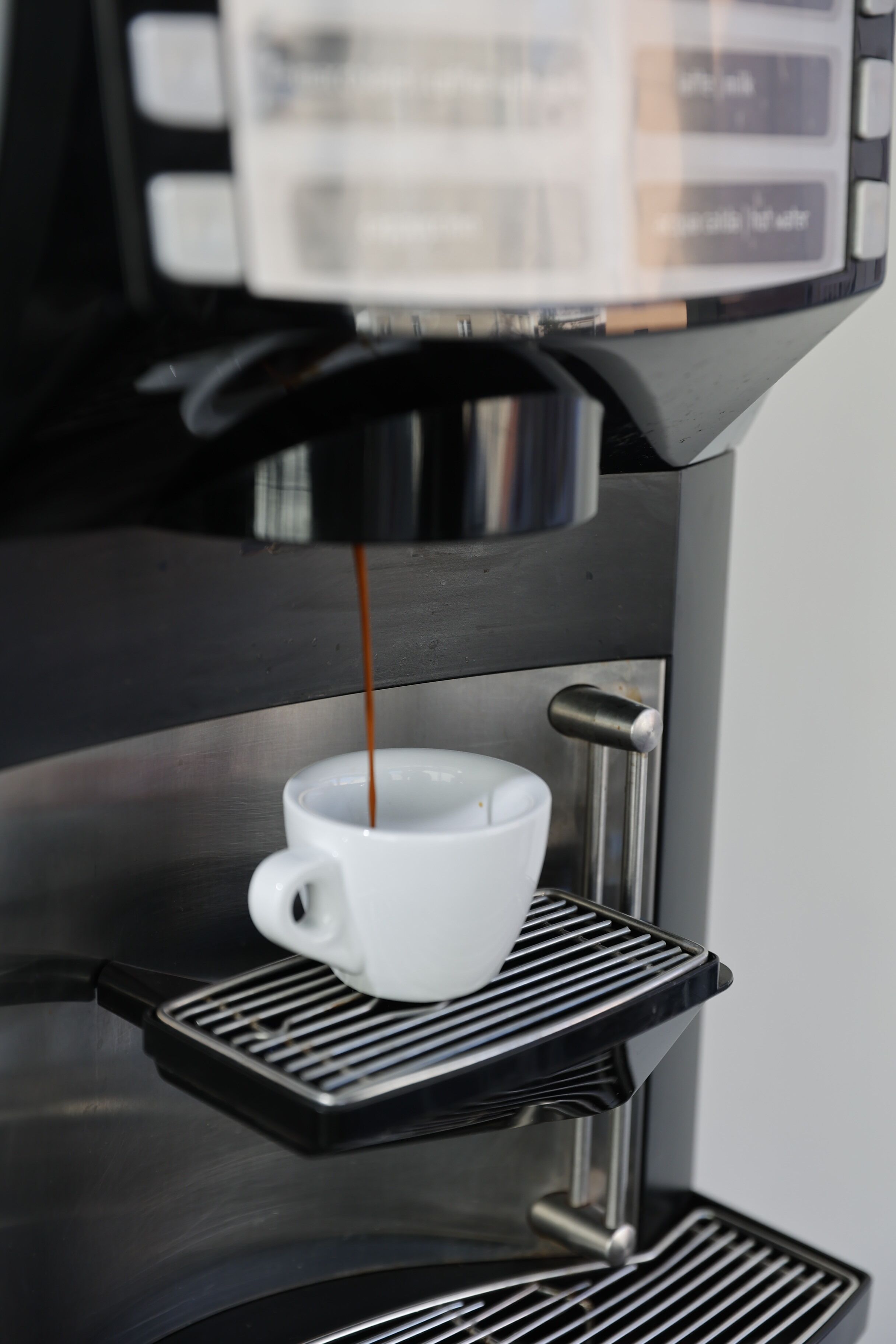 Una cafetera sirviendo café en una taza.