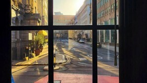 A street view through a window with buildings on either side, a clear sky, and a car on the road. - Stunning Apartment in Leeds (Leeds)