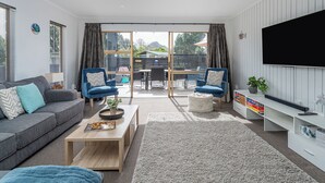 Un salon moderne comprenant un canapé, deux fauteuils, une table basse et un téléviseur.
