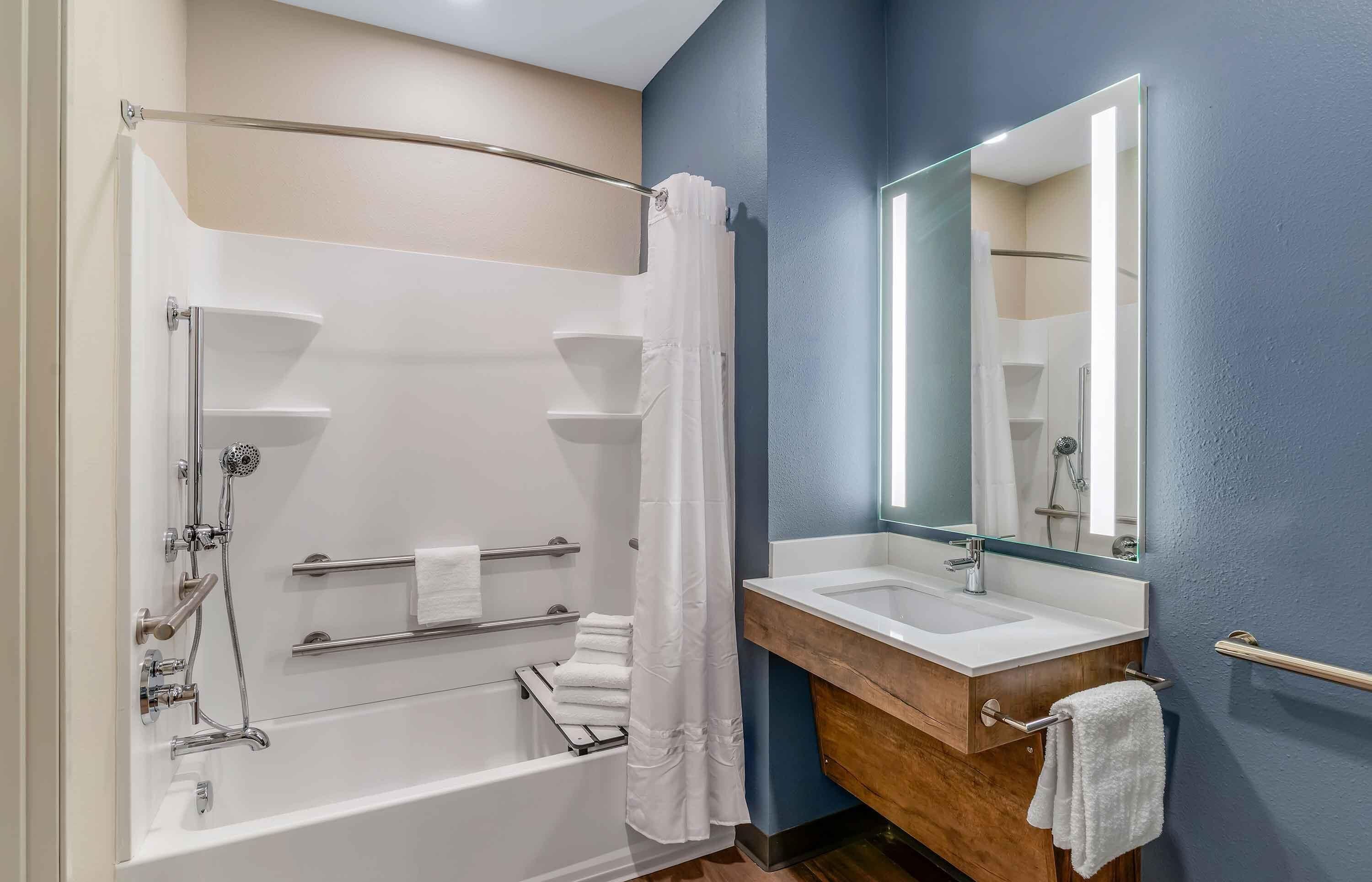 A modern bathroom with a bathtub, shower, and dual sinks.