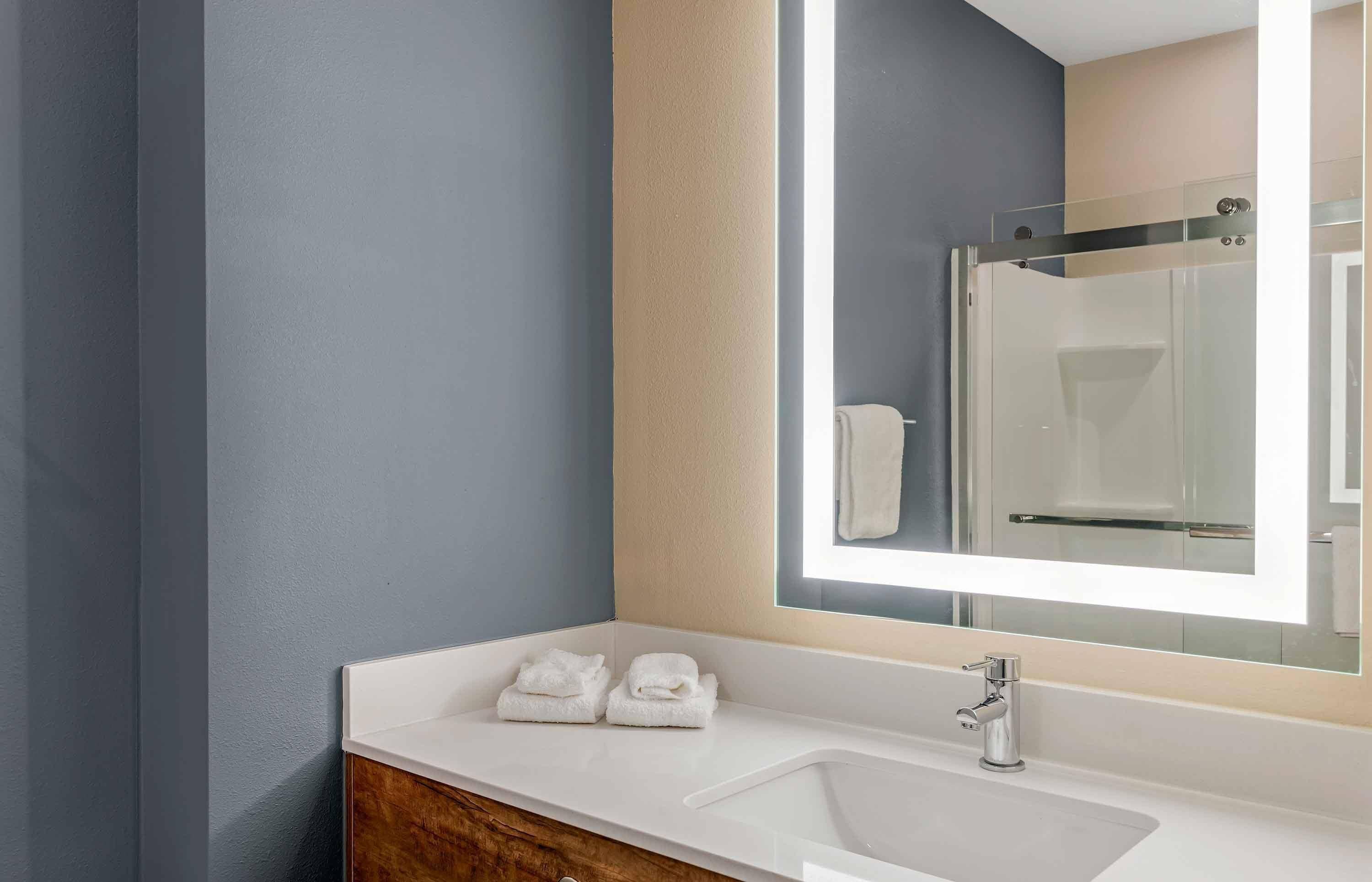 A modern bathroom with a white sink, a large mirror, and a glass shower enclosure.