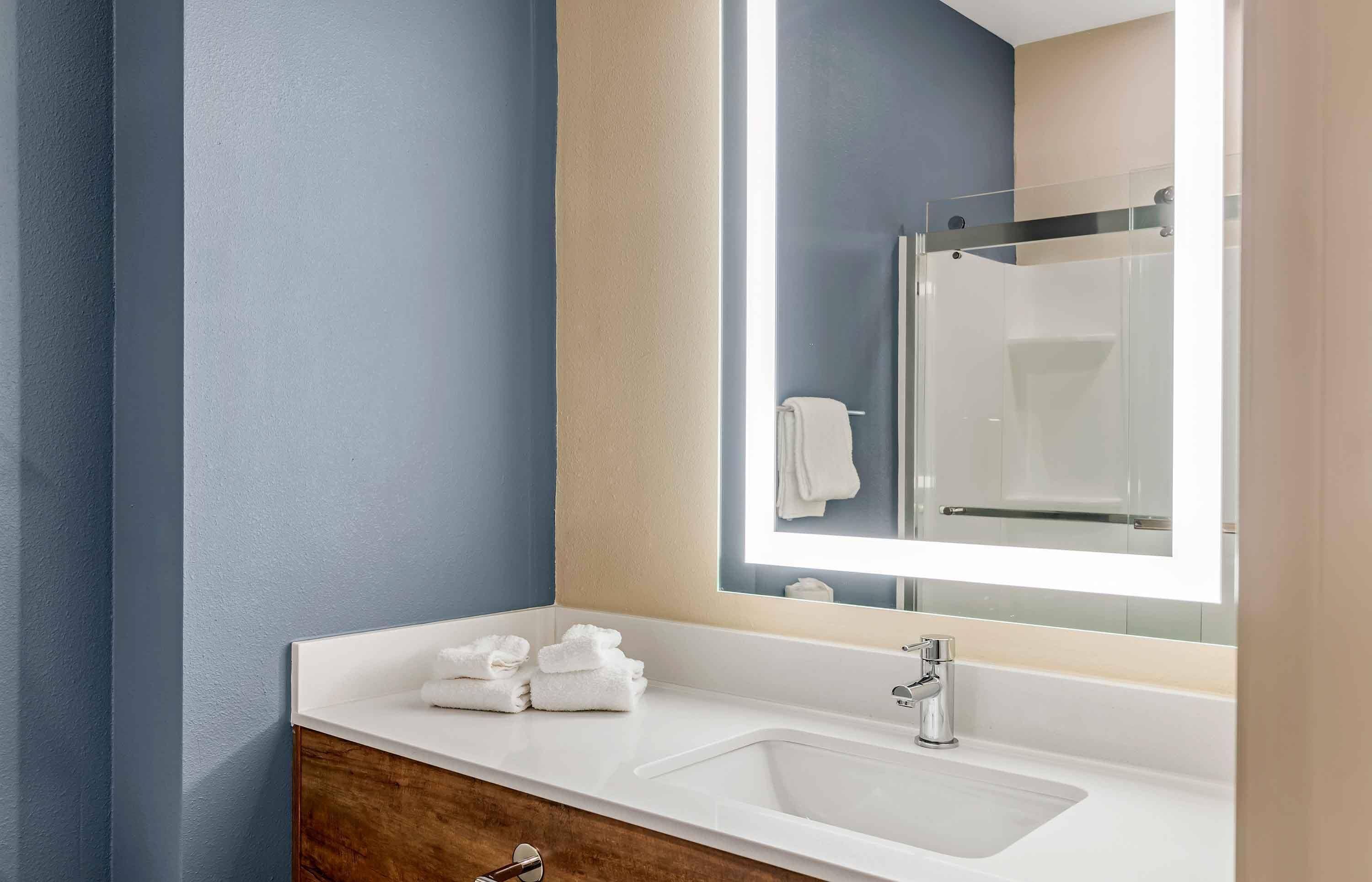 A modern bathroom with a white sink, a large mirror, and a glass shower enclosure.