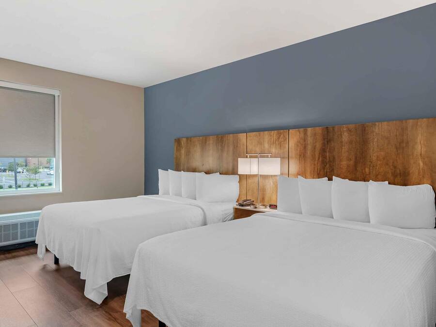 A hotel room with two beds, a large window, and a wooden headboard.