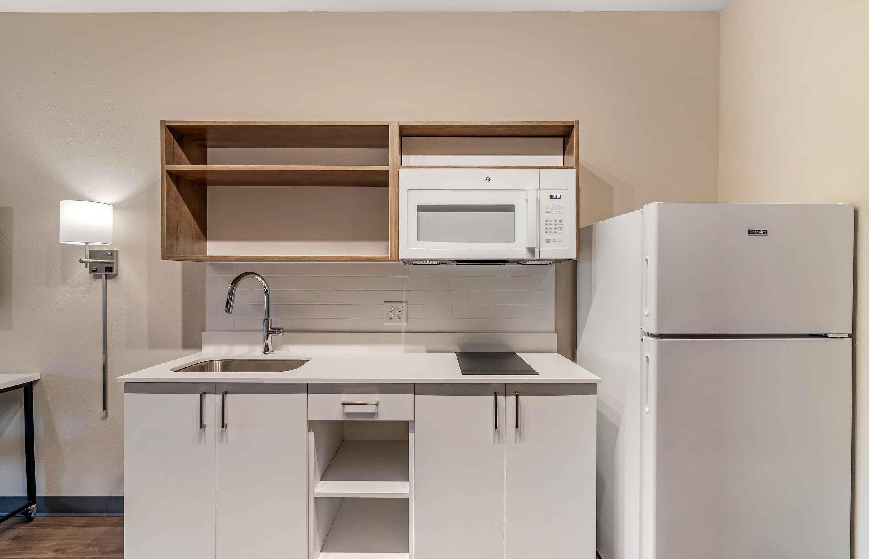 Una cocina moderna con armarios blancos, un microondas integrado y un refrigerador.
