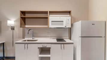 Una cocina moderna con armarios blancos, un microondas integrado y un refrigerador.