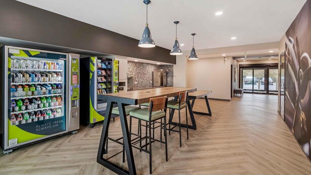 A modern indoor space with vending machines, a wooden table, and chairs.