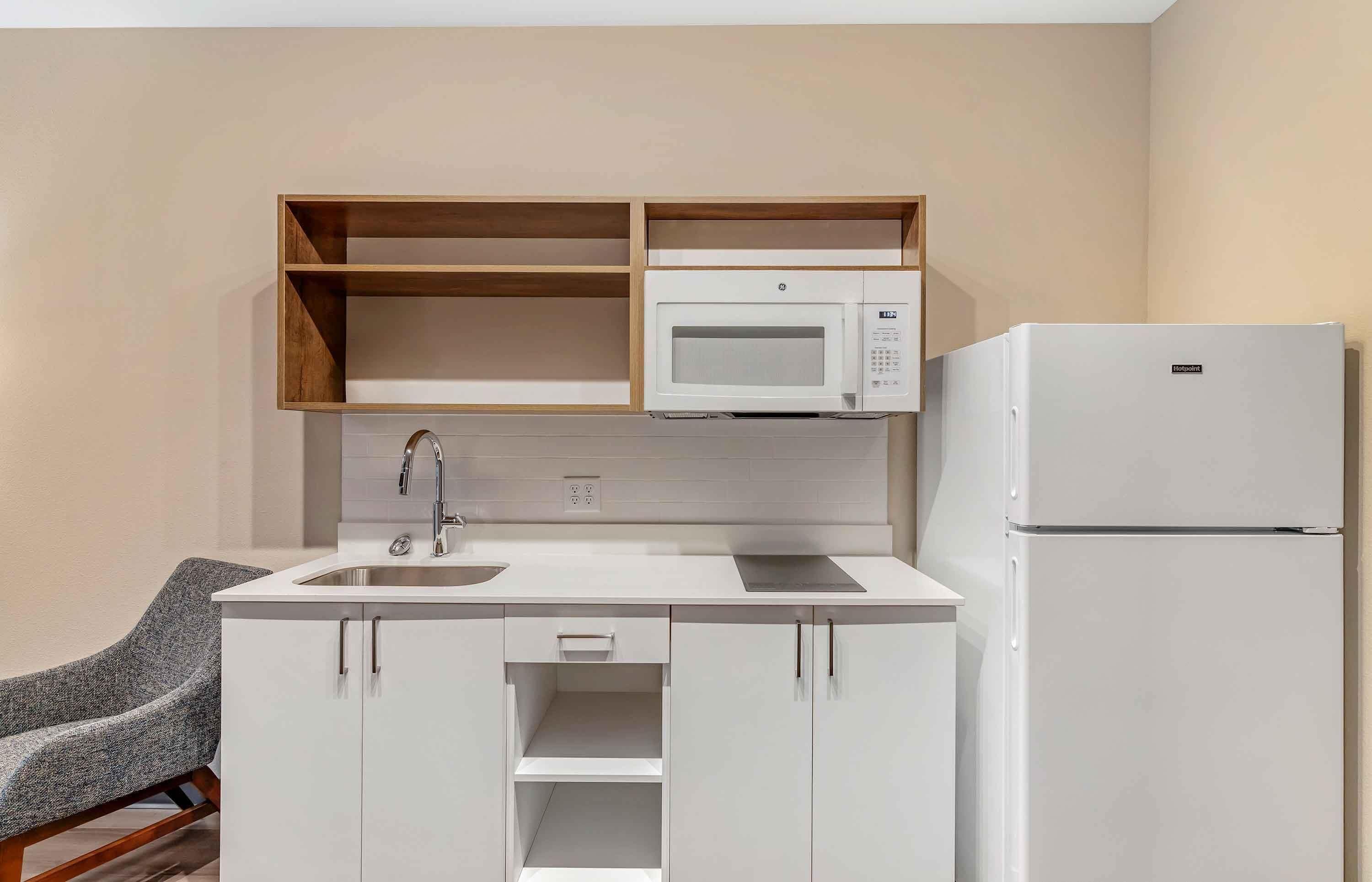 A compact kitchenette with a microwave, sink, and refrigerator.