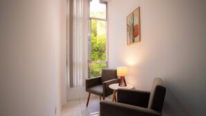 A modern room with a large window, a chair, a small table, and a lamp. - SUH Copacabana 63 Peace Beach (Rio de Janeiro)