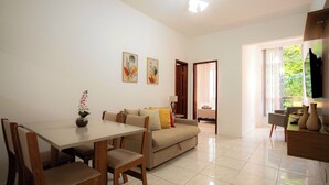 A modern living room with a sofa, dining table, and chairs. There is a ceiling fan, a window with curtains, and a door leading to another room. - SUH Copacabana 63 Peace Beach (Rio de Janeiro)
