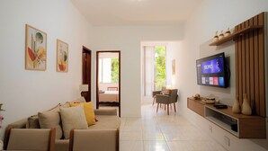 A modern living room with a sofa, TV, and a dining area with chairs. - SUH Copacabana 63 Peace Beach (Rio de Janeiro)