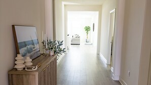 A hallway with a wooden console table, a framed picture, and a potted plant. - The Palms Hideaway - Desert Luxury (La Quinta)