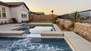A swimming pool with a hot tub, surrounded by a brick wall and a fence. - The Palms Hideaway - Desert Luxury (La Quinta)