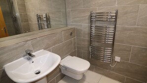 A bathroom with a white sink, a toilet, and a towel rack. - Exceptional Two-Bedroom Apartment in the City Center. (Birmingham)