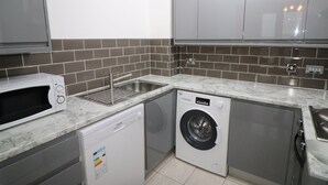 A compact kitchen with a microwave, dishwasher, and washing machine. - Exceptional Two-Bedroom Apartment in the City Center. (Birmingham)