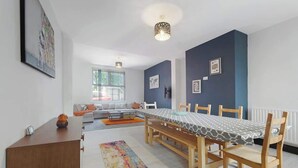 A dining area with a long table, chairs, and a patterned rug.
