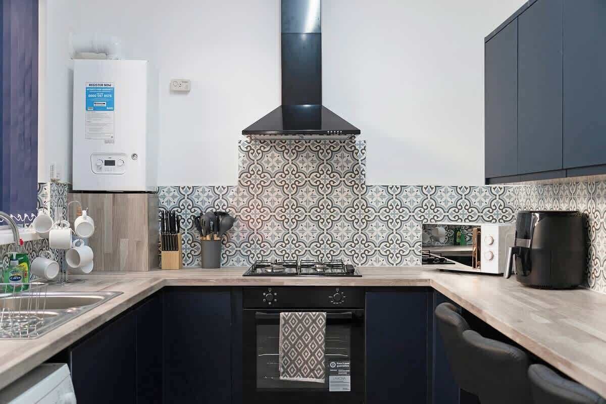 Una cucina con piano cottura a gas, forno ventilato, macchina per il caffè e scaldabagno.