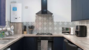 A kitchen with a gas stove, a built-in oven, a coffee maker, and a water heater.