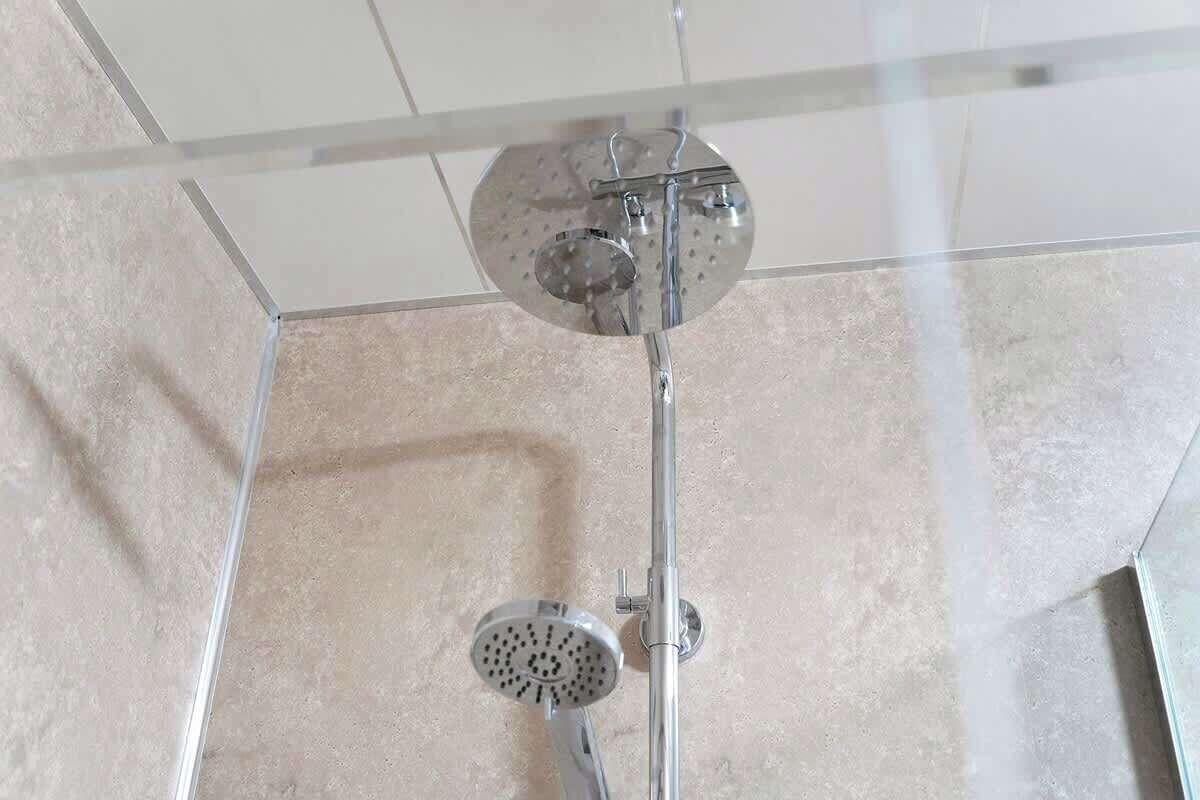 Eine Dusche mit Duschbrause und Wandarmatur.