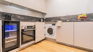 A compact kitchen with a built-in oven, a washing machine, and a marble backsplash. - Rezia Apartments by Rent All Como (Como)