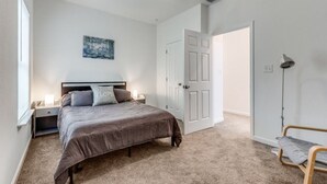 A bedroom with a bed, bedside tables, a ceiling fan, a door, and a floor lamp.