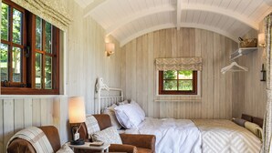 A cozy bedroom with two beds, a wooden ceiling, and a window with a view of greenery. - Barn Owl Hut - UK49769 (Westerdale, near Whitby)