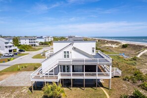 A coastal house with a large deck, a garage, and a view of the beach. - Deck & View: Oceanfront Oasis in Oak Island! (Oak Island)