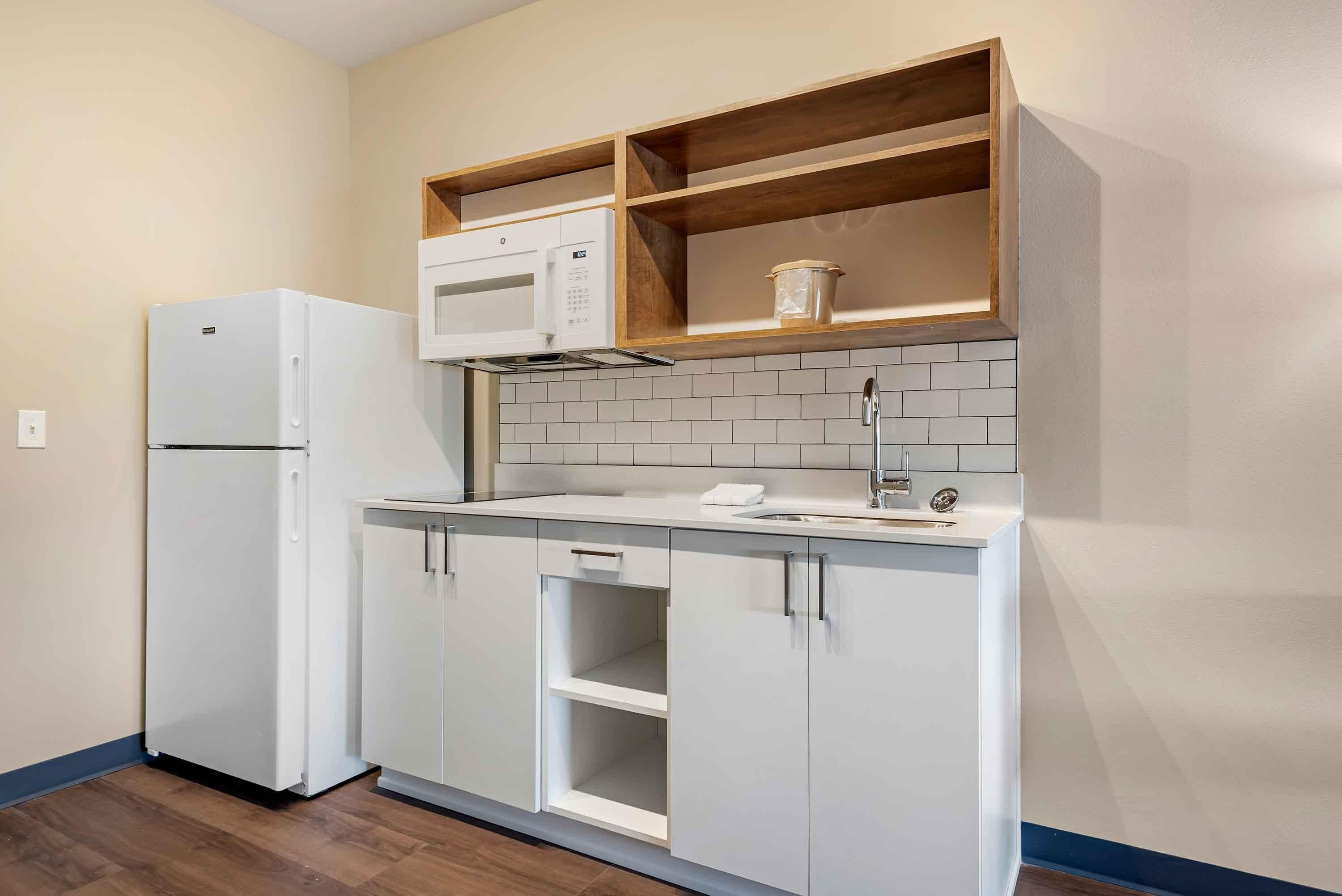 A compact kitchen with white cabinetry, a built-in microwave, and a sink.
