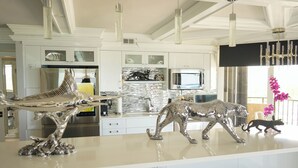 Une cuisine moderne dotée d’un îlot central, d’appareils électroménagers en acier inoxydable et de figurines animales décoratives.