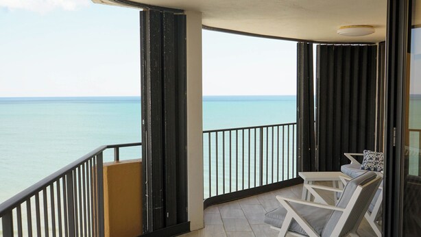 Un balcon avec vue sur la mer, une statue et un espace détente avec une table et des chaises.