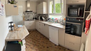 A modern kitchen with white cabinets, a tiled backsplash, a built-in oven, and a window providing natural light. - HOUSE SLEEPS 8 SEASIDE - PRIVATE POOL - ENCLOSED PARK - PRIVATE PARKING (Saint-Cyprien)