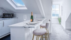 A modern kitchen with a skylight, a bar area with a bottle of champagne, and a view of the sea.