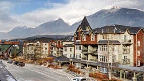 A row of multi-story buildings with balconies, set against a backdrop of snow-capped mountains. - Alpine Loft Penthouse [Outdoor Heated Pool & x3 Hot Tubs] (Canmore)