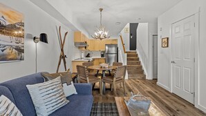 A modern apartment with a living room, dining area, kitchen, and staircase. - Alpine Loft Penthouse [Outdoor Heated Pool & x3 Hot Tubs] (Canmore)