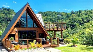 A wooden cabin with a triangular roof, large windows, and a deck. - Romantic Chalet Arcadia (Unknown)