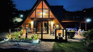 A wooden cabin with a triangular roof, a deck with outdoor seating, and a small pool area. - Romantic Chalet Arcadia (Unknown)