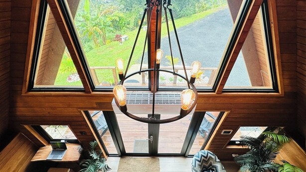 A spacious room with a large skylight, a modern chandelier, and a view of a lush garden. - Romantic Chalet Arcadia (Unknown)