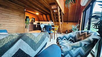 A cozy cabin interior with a dining area, kitchen, and a large window providing natural light.