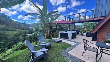A patio area with Adirondack chairs, a hot tub, and a table with chairs.