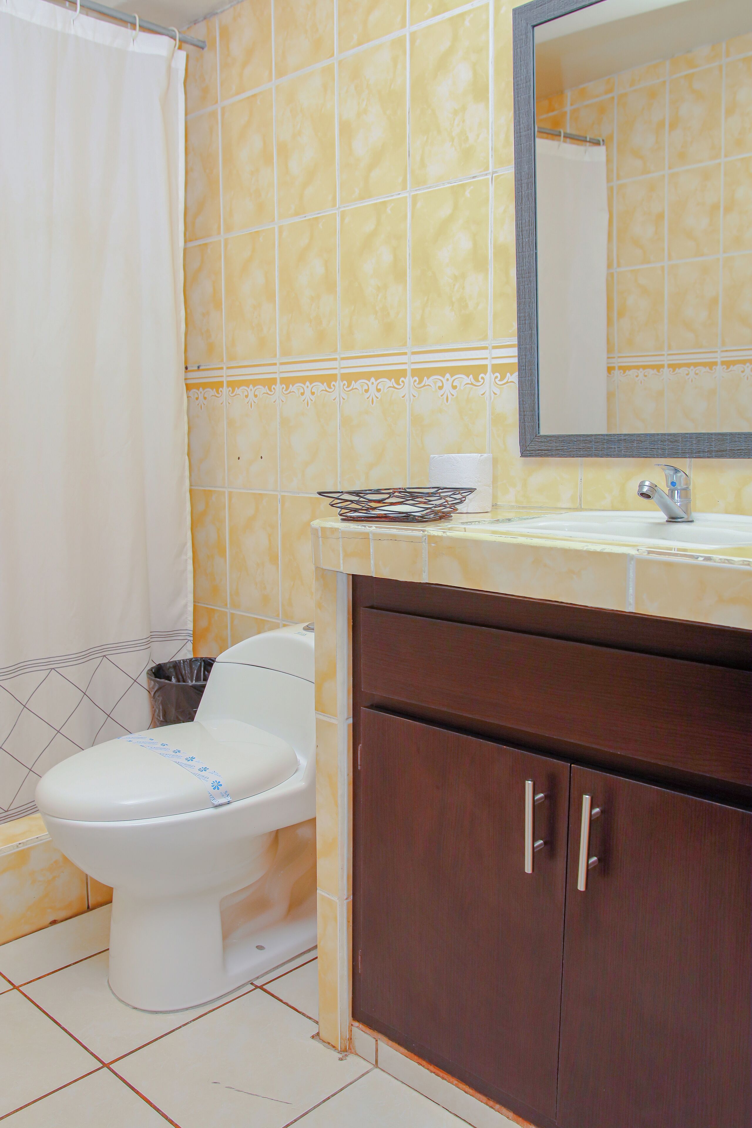 A bathroom with a toilet, sink, and mirror.