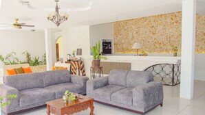 Un salon moderne avec deux canapés gris, une table basse en bois et un mur décoratif en pierre.