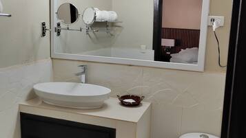 A bathroom with a white sink, a mirror with lights, a black cabinet, and a toilet.