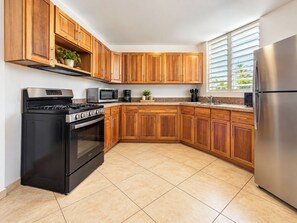 A kitchen with wooden cabinets, a stainless steel refrigerator, a stove, a microwave, and a coffee maker.