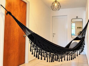 A hammock in a hallway with a wooden door and a white wall.