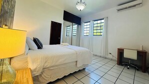 A hotel room with a bed, a desk, a lamp, and a window with curtains.