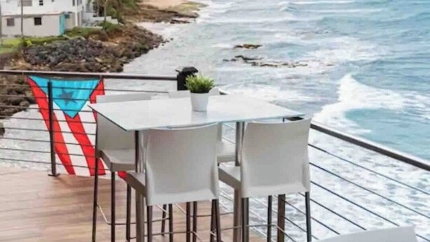 A deck with a view of the ocean, featuring a table and chairs.