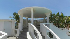 A white, modern architectural structure with a circular roof and a staircase leading to it.