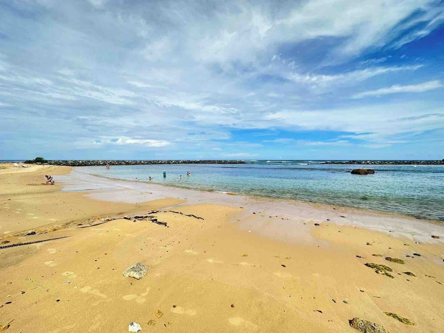 Ein Strand mit blauem Himmel und ruhigem Wasser.
