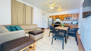 A compact living space with a sofa, ottoman, and dining table with chairs. A ceiling fan and recessed lighting are visible. - Paradise Beach Apartment Vieques 6 (Vieques)