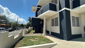 A modern two-story building with a flat roof, large windows, and a small front garden. - Paradise Beach Apartment Vieques 6 (Vieques)
