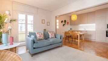 Una sala moderna con sofá, mesa de comedor y zona de cocina.